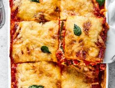 square lasagna casserole with basil leaves on top in a white dish