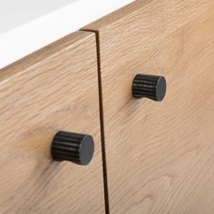 two black knobs on the side of a wooden cabinet