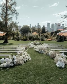 an outdoor ceremony setup with white flowers and greenery in the foreground, cityscape in the background