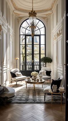 a living room filled with furniture and a chandelier hanging from the ceiling over a wooden floor