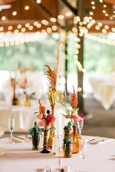 two vases filled with flowers on top of a white table cloth covered tablecloth