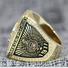 a gold ring with an emblem on the side and diamonds around it, sitting on top of a piece of fabric