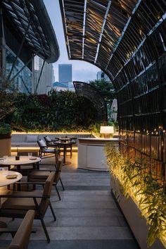 an outdoor dining area with tables and chairs under a canopy over the patio at night