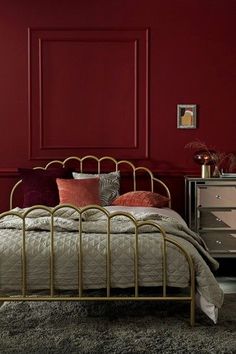 a bedroom with red walls and gold bed frame