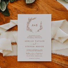 the wedding stationery is laid out on a table with white linens and greenery