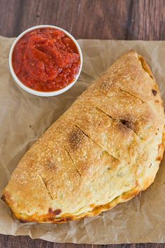 a large piece of bread with sauce on it next to a bowl of ketchup