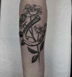 a black and white photo of a flower tattoo on the left arm, with an arrow in the middle