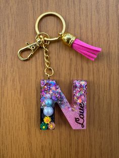 the letter n is decorated with beads and tassels on a keychain