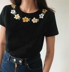 a woman wearing a black shirt with flowers on it's chest and short sleeves