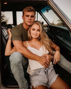 a man sitting on the back of a truck next to a woman in denim shorts