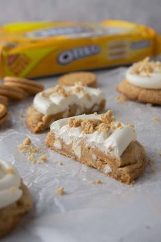 several cookies with white frosting and pecans on the side next to a carton of milk