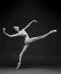 a woman in white leotard and ballet shoes is doing a split leg pose