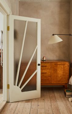 an open door leading to a bedroom with wooden flooring and white walls in the background