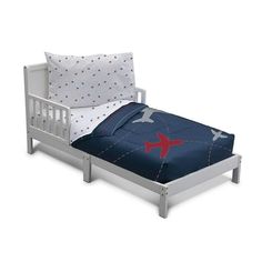 a white bed with a blue comforter and red airplane pillow on the top of it