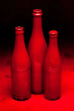 three red glass bottles sitting next to each other