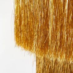 closeup of gold tinsel hanging from the side of a pole with white background