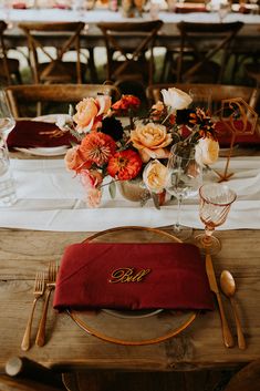 the table is set with red napkins and place settings, along with orange flowers