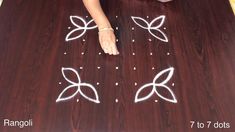 a woman is drawing on the floor with white chalk and some beads in front of her