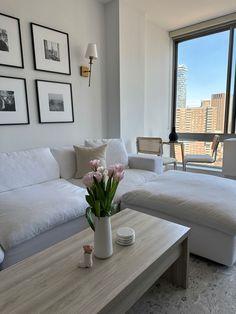 a living room filled with furniture and a large window overlooking the cityscape in black and white