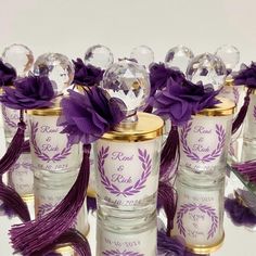 several glass jars with purple flowers and ribbons on them are lined up in front of each other