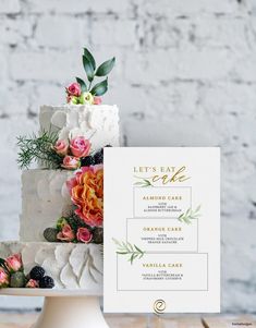 a wedding cake with flowers and greenery sits on a table next to a sign that says let's eat