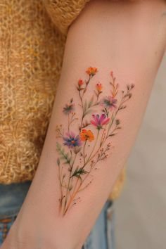 a woman's arm with flowers painted on it and an orange flower in the center