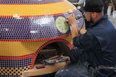 a man is working on a large mosaic piece