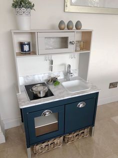 a small kitchen with blue cabinets and white counter tops, including a sink in the center