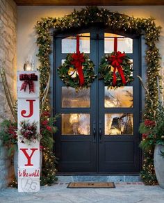 two christmas wreaths on the front door of a house