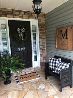 the front porch is decorated with black and white plaid pillows, wreaths, and monogrammed door mats