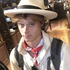 a young man wearing a hat and suspenders