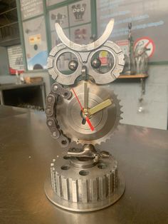 a clock made to look like an owl with gears on it's face sitting on top of a table