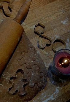 a wooden table with cookie cutters, candle and other baking supplies on top of it