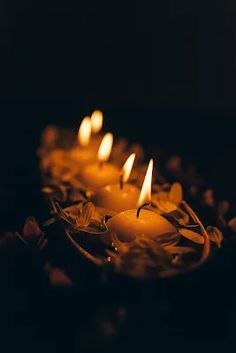 several lit candles sitting on top of each other in a circle with petals around them