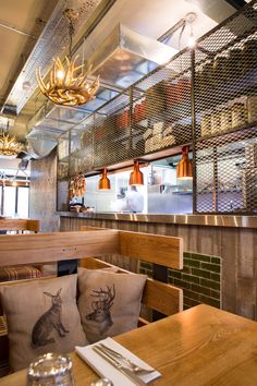 the interior of a restaurant with wooden tables and chairs, lights hanging from the ceiling