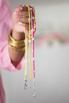 a woman is holding several bracelets in her hand and she has pink fingernails on