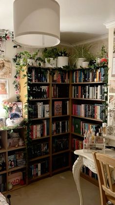 a room filled with lots of books and plants on top of wooden shelving units