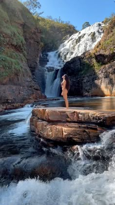 a woman standing on the edge of a waterfall