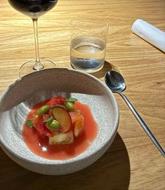 there is a small bowl with some food in it next to a glass of wine