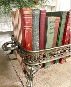 some books are in a metal holder on a shelf next to a christmas tree and pine branches