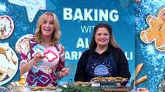 two women standing behind a table with food on it