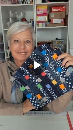 a woman holding up a piece of quilt