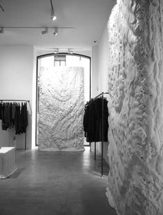 a room filled with lots of white clothing on display next to a wall covered in fake fur