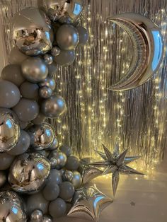 silver balloons and stars are hanging from the ceiling in front of a curtained wall