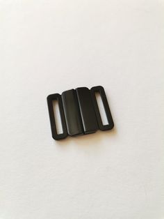 three black plastic buckles sitting on top of a white surface