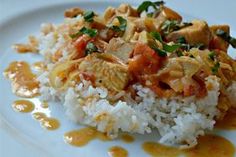 a white plate topped with rice and meat covered in sauce