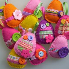 several colorful felt pieces with buttons and bows on them are arranged in the shape of hearts