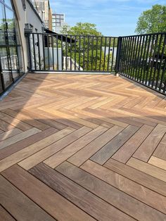 a wooden deck with black iron railings and glass doors