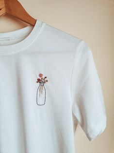 a white t - shirt with flowers in a mason jar embroidered on the front