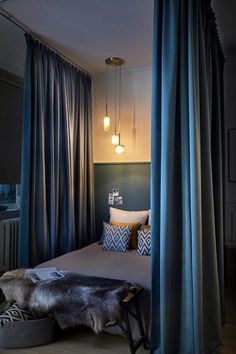 a bed with blue curtains and pillows in a room